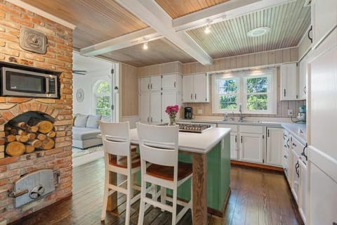 5 burner stove & oven island with two chairs. Microwave and beautiful brick area