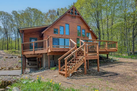 - Cabin exterior with tall windows wood siding and wide deck - Forest backdrop surrounds this inviting nature retreat - Elevated outdoor space perfect for relaxing and gathering