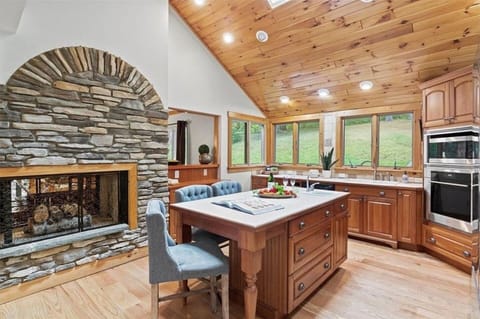 Enjoy culinary delights in a fully-equipped kitchen with custom wood cabinetry and a cozy dining nook, all accentuated by a stunning stone fireplace.