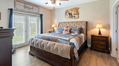 Cozy master bedroom featuring a king bed with tufted headboard, bear themed decor, nightstands, and ceiling fan at A Sleepy Bear Getaway condo in Pigeon Forge, Tennessee