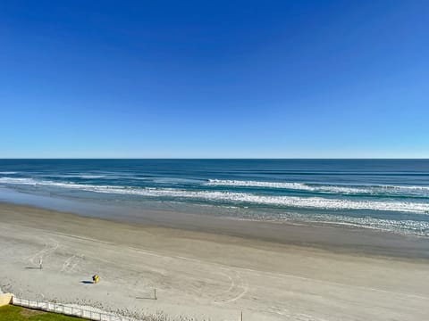 Enjoy the calming views of the expansive blue ocean meeting the horizon under clear skies.