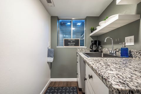 The cozy kitchenette is ideal for quick meals and morning coffee, offering a sleek granite countertop, sink, Keurig, mini fridge, and all the basics for a convenient stay.