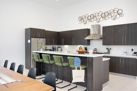 Fully-equipped kitchen with modern appliances and barstool seating at the counter.
