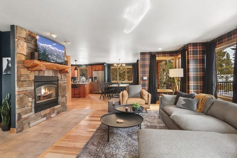 Gather in the great room, featuring a Roku Smart TV and surrounded by rustic log beams and stairwells, blending modern convenience with mountain charm.