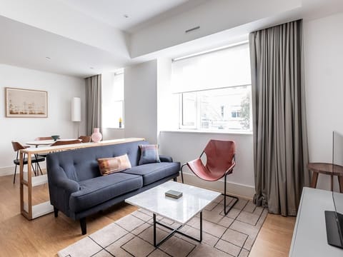 Deluxe apartment with light and airy lounge area, with sofa, table, chairs.