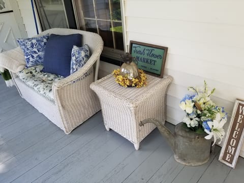 Farmhouse wicker furniture on side porch near main entrance