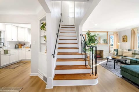 Bright staircase w/ wood steps & open railings connecting airy interiors