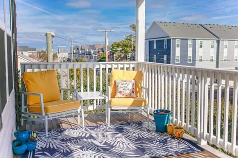 Balcony with two chairs, side table, a rug, and plants.