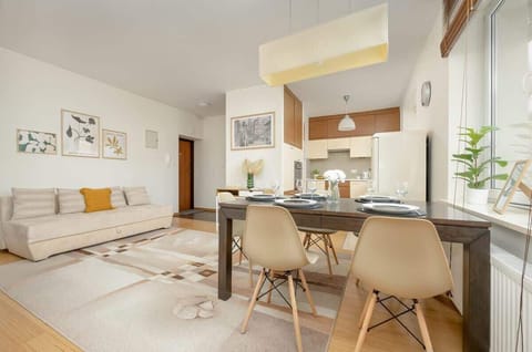 A beautiful dining setup with a wooden table, neutral-toned chairs, and a soft lighting fixture, perfect for hosting guests.

