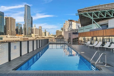 Enjoy a relaxing swim in the shared outdoor lap pool, heated for comfort, with a backdrop of city skyline views.