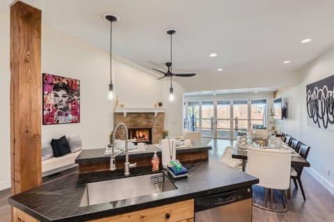 Relax in this bright, open-plan space. It features a modern kitchen island and a cozy living area with a stone fireplace, perfect for unwinding after your adventures.