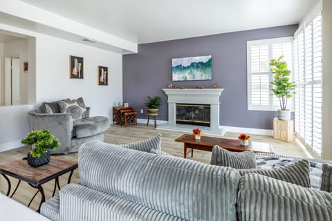 Cozy gray living room with fireplace, soft décor, and natural light flow