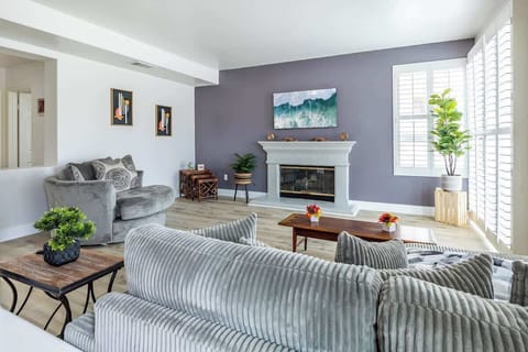 Family Room: Gray sofa, fireplace, and soft décor create a cozy, light-filled retreat