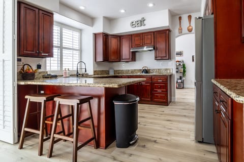 Modern kitchen with island seating, wood cabinets, and natural light.