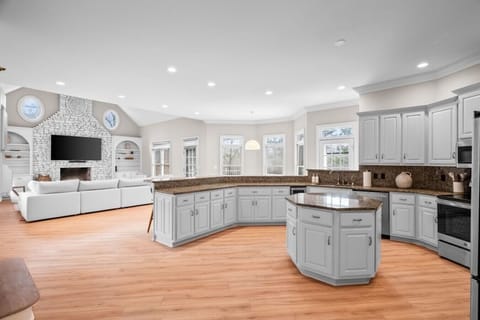 Large, open concept kitchen & family room featuring an 80 inch tv & high vaulted ceilings.