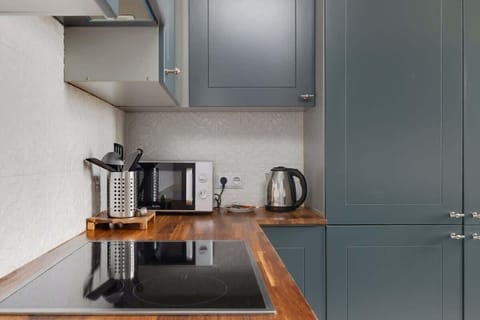A kitchen corner with navy-blue cabinetry, a wooden countertop, and modern appliances, offering a functional and stylish cooking space.