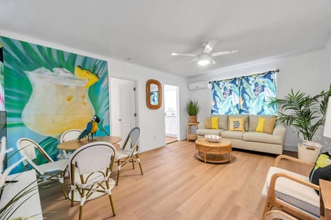 Bright living area w/ cozy seating, natural light, and bold tropical wall art that adds a fun pop of color.