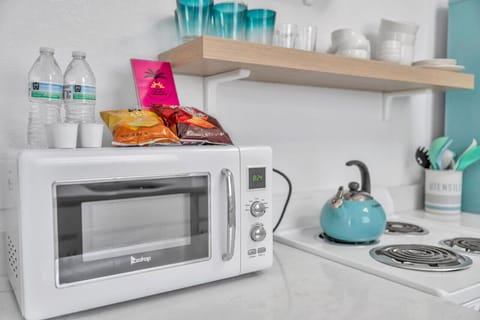 Compact kitchen setup w/ microwave, kettle, and neatly styled essentials for quick bites