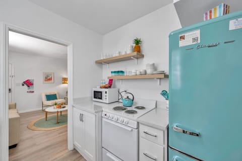 Bright galley kitchen w/ turquoise fridge, open shelving, and a clean, coastal vibe