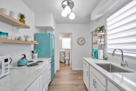 Fresh kitchen w/ turquoise fridge, open shelving, and a clean, breezy feel
