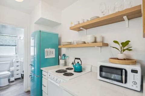 Compact kitchen w/ open shelving, prep space, & cheerful touches throughout.