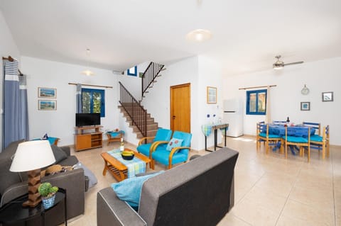 Open-plan living room with sofas, dining area, kitchen, A/C, WiFi internet, and satellite TV