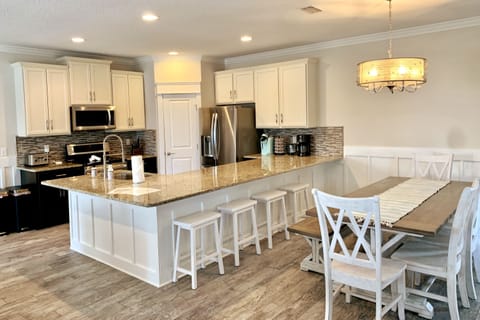 Big, open, well-supplied kitchen with breakfast bar and large dining table.