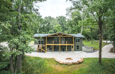 Aerial of back of home showing layout of deck, patio, firepit, driveway.