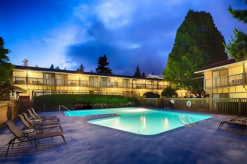 Unwind at dusk with a glowing pool and quiet lounge chairs.