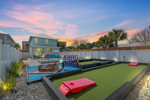 Inviting backyard oasis complete with corn hole, a kids` play zone, and a life-sized kick pool, ensuring endless fun and entertainment for all ages