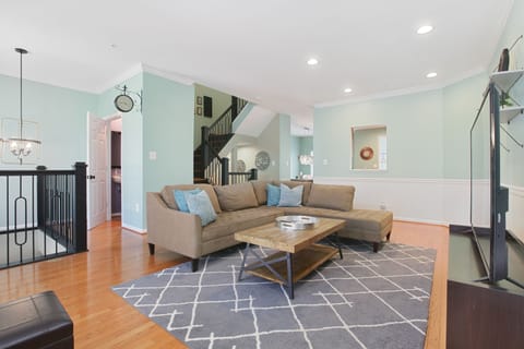 Vibrant, roomy living area! High ceilings, 65" smart TV & L-shaped sofa.