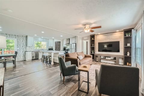 Open floor plan with dining room, bar seating, living room with large TV, couches and chairs