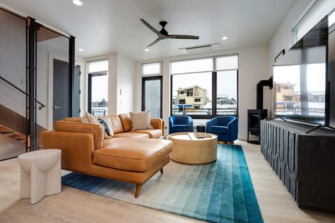 Relax in your stylish living space with plush leather seating, modern blue accents, and bright windows overlooking the neighborhood.