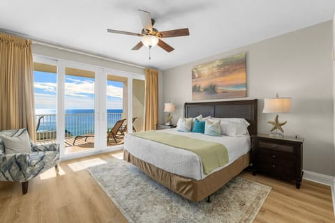 Elegant master bedroom featuring a king-size bed, serene coastal décor, and private balcony access with stunning ocean views