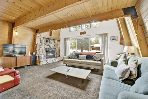 Cozy mountain living room with a stone fireplace, comfy seating, and smart TV—perfect for relaxing evenings, movie nights, and warm cabin vibes after outdoor adventures.