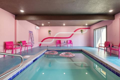 Playful indoor pool with bold pink accents, lounge seating, and a fun, retro vibe.