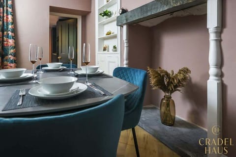 Welcome to the heart of Wainwright Apartment – an inviting dining setup in the living room, featuring an extendable table and plush velvet chairs elegantly arranged for a cozy dining experience.