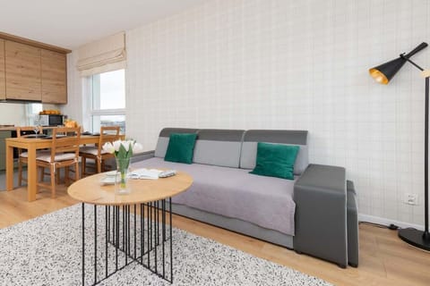 A spacious living and dining area with a neutral color scheme, a large window, and a stylish combination of furniture.