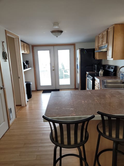 View of kitchen from breakfast bar. Kitchen walks out onto deck. 