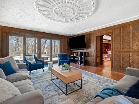 Stylish living room w/ blue sofas, wood paneling & a statement ceiling medallion—perfect for relaxed gatherings.