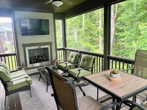 Screened in porch with seating area, dining table for 4, TV, and gas fireplace