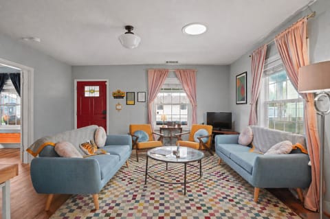A bright, mid-century inspired living room with bold colors, clean lines, and plenty of natural light. Settle in on the cozy seating with a cup of coffee, stream your favorite show, or gather with friends in this warm, inviting space.