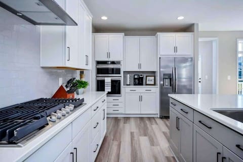 Experience culinary delights in our spacious, fully stocked kitchen featuring a sprawling island, gleaming stainless steel appliances, and a generously stocked pantry for all your cooking needs.