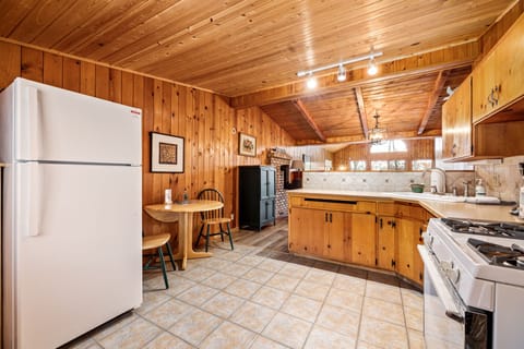 Indulge in our cozy, wood-paneled kitchen, complete with modern amenities, a charming dining area, and inviting warm lighting. It's the perfect fusion of rustic charm and contemporary comfort for your stay.