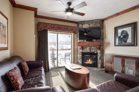 - Gather in the living room featuring a stone fireplace and smart TV  
- Comfortable leather seating with direct access to the private balcony  
- Warm up after skiing while enjoying mountain views from indoors