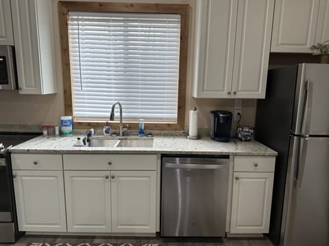 Kitchen sink, granite countertops, dishwasher, and Keurig coffee maker.