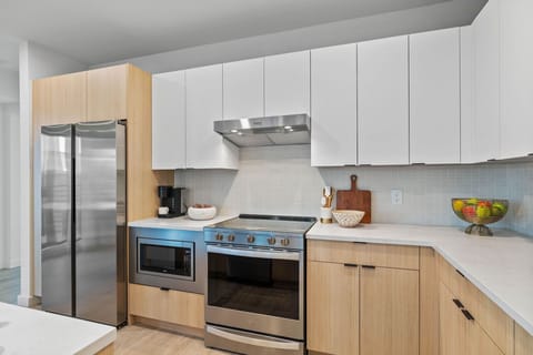 Fully equipped modern kitchen featuring culinary essentials, stainless steel appliances, and island bar seating.