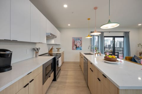 Fully equipped kitchen stocked with all culinary essentials and featuring brand-new stainless-steel appliances and a large kitchen island offering bar seating.