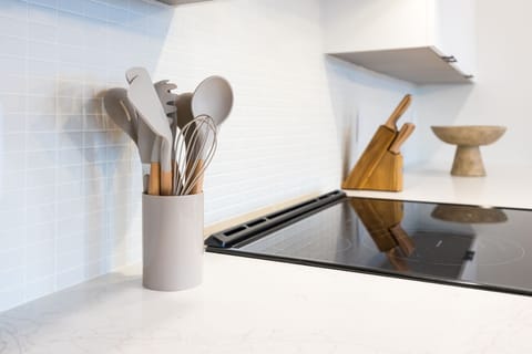 Fully equipped kitchen stocked with all culinary essentials and featuring brand-new stainless-steel appliances and a large kitchen island offering bar seating.