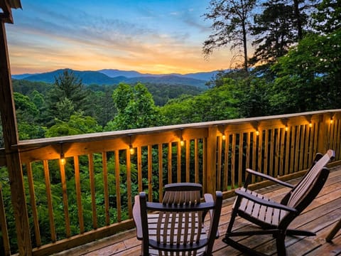 Cozy mountain-view deck with string lights and serene sunset scenery.